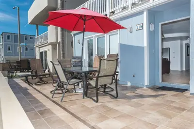 a table and chairs with a red umbrella on a patio at Pet-Friendly 3Br W Ac, Oceanview Patio, Steps From Beach By Beachview Rentals in Newport Beach