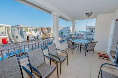 a balcony with chairs and tables and a view of the ocean at Spacious 4Br W Oceanview Balcony, 3 Houses From The Beach By Beachview Rentals in Newport Beach