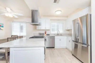 a kitchen with white cabinets and a stainless steel refrigerator at Spacious 4Br W Oceanview Balcony, 3 Houses From The Beach By Beachview Rentals in Newport Beach