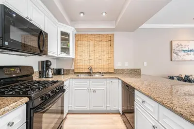 a kitchen with white cabinets and a stove top oven at Pet-Friendly 3Br Retreat W Large Patio Steps From Beach By Beachview Rentals in Newport Beach