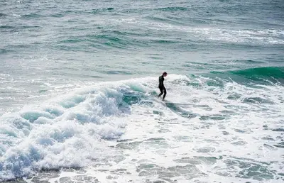 a man riding a wave on a surfboard in the ocean at Family-Friendly 2Br Beach Home In Prime Walkable Location By Beachview Rentals in Newport Beach