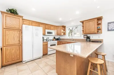 a kitchen with wooden cabinets and a white refrigerator at Family-Friendly 2Br Beach Home In Prime Walkable Location By Beachview Rentals in Newport Beach