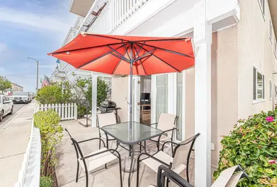 a table and chairs with an umbrella on a patio at Family-Friendly 2Br Beach Home In Prime Walkable Location By Beachview Rentals in Newport Beach