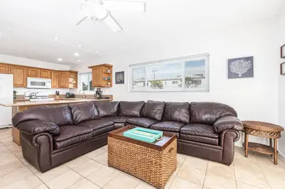 a living room with a brown leather couch and a kitchen at Family-Friendly 2Br Beach Home In Prime Walkable Location By Beachview Rentals in Newport Beach