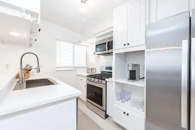 a kitchen with white cabinets and a stainless steel refrigerator at Upgraded Pet-Friendly Home Steps From Popular 40Th St Beach By Beachview Rentals in Newport Beach