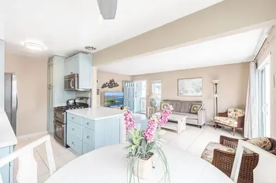 a kitchen and living room with a table with flowers at Upgraded 5Br Summer Vacation Home, Steps From The Sand By Beachview Rentals in Newport Beach