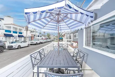 a wooden table with an umbrella on a balcony at Remodeled 3Br W Oceanview Patio, Ac, 4 Houses From Sand By Beachview Rentals in Newport Beach