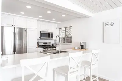 a white kitchen with white cabinets and white appliances at Renovated 2Br W Oceanview Patio Steps From 40Th St Beach By Beachview Rentals in Newport Beach