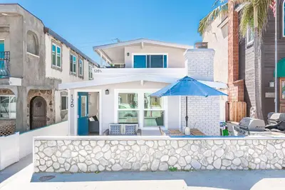 a house with a stone wall and an umbrella at Renovated 2Br W Oceanview Patio Steps From 40Th St Beach By Beachview Rentals in Newport Beach