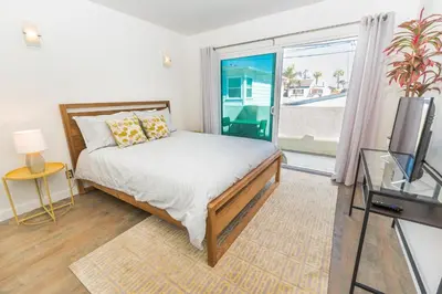 a bedroom with a bed and a tv and a window at Modern Oceanview Tri-Level Condo Steps From The Beach By Beachview Rentals in Newport Beach