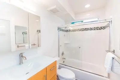 a white bathroom with a sink and a shower at Modern Oceanview Tri-Level Condo Steps From The Beach By Beachview Rentals in Newport Beach