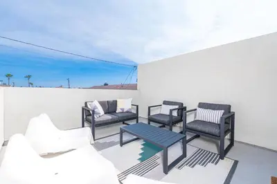 a patio with chairs and a table on a wall at Modern Oceanview Tri-Level Condo Steps From The Beach By Beachview Rentals in Newport Beach