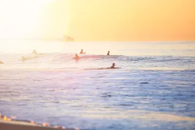 a group of people surfing in the ocean at Modern Oceanview Tri-Level Condo Steps From The Beach By Beachview Rentals in Newport Beach