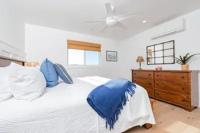 a bedroom with a white bed with blue pillows at Luxury 4Br Coastal Retreat W Rooftop Deck And Ocean Views By Beachview Rentals in Newport Beach