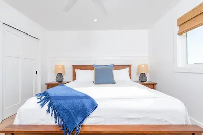 a bedroom with a bed with a blue blanket on it at Luxury 4Br Coastal Retreat W Rooftop Deck And Ocean Views By Beachview Rentals in Newport Beach