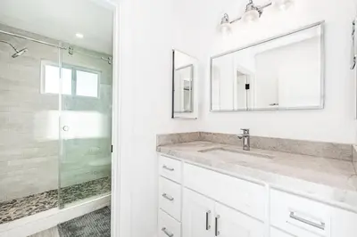 a white bathroom with a sink and a shower at Luxury 4Br Coastal Retreat W Rooftop Deck And Ocean Views By Beachview Rentals in Newport Beach