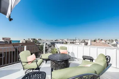 a balcony with a table and chairs and the beach at Luxury 4Br Coastal Retreat W Rooftop Deck And Ocean Views By Beachview Rentals in Newport Beach