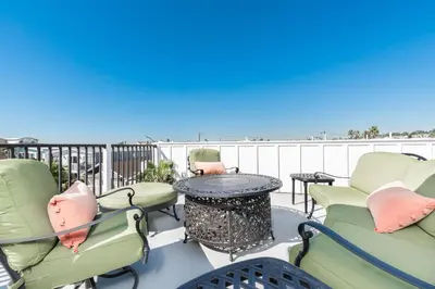 a patio with chairs and a table and the beach at Luxury 4Br Coastal Retreat W Rooftop Deck And Ocean Views By Beachview Rentals in Newport Beach