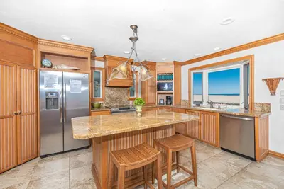 a kitchen with a large island with stools at Oceanfront 2Br W Ac, Updated Interior, And Panoramic Views By Beachview Rentals in Newport Beach