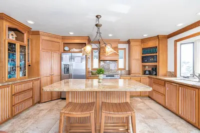 a kitchen with wooden cabinets and a island with stools at Oceanfront 2Br W Ac, Updated Interior, And Panoramic Views By Beachview Rentals in Newport Beach