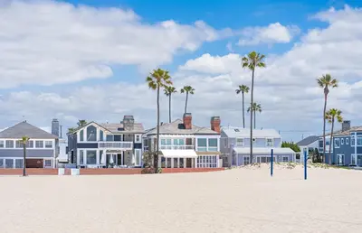 a row of houses on the beach with palm trees at Cozy 2Br Cottage W Ac, Prime Location One House From Sand By Beachview Rentals in Newport Beach