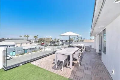 a patio with a table and chairs on a balcony at Luxury 4Br Tri-Level W Modern Interior, Rooftop Deck, Ac By Beachview Rentals in Newport Beach