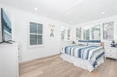 a white bedroom with a bed and some windows at Updated 2Br Vintage Cottage In Central Location Near Beach By Beachview Rentals in Newport Beach