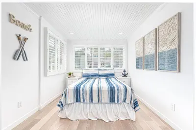 a white bedroom with a bed in a room with windows at Updated 2Br Vintage Cottage In Central Location Near Beach By Beachview Rentals in Newport Beach