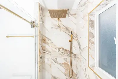 a shower in a bathroom with a marble wall at Updated 2Br Vintage Cottage In Central Location Near Beach By Beachview Rentals in Newport Beach