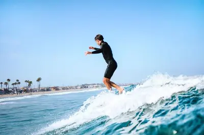 a man riding a wave on a surfboard in the ocean at Updated 2Br Vintage Cottage In Central Location Near Beach By Beachview Rentals in Newport Beach