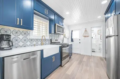 a kitchen with blue cabinets and stainless steel appliances at Updated 2Br Vintage Cottage In Central Location Near Beach By Beachview Rentals in Newport Beach