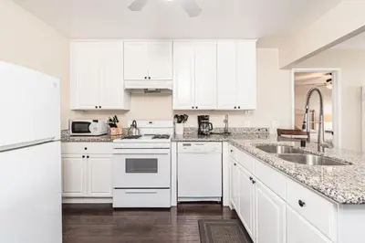 a white kitchen with white cabinets and a sink at Cozy 1Br Beach Retreat W Balcony, One Block From The Sand By Beachview Rentals in Newport Beach