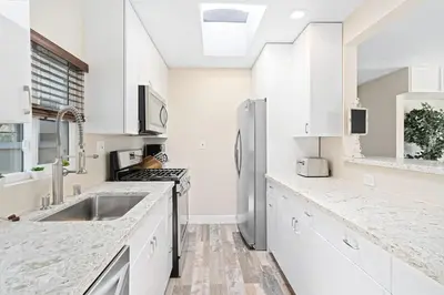a kitchen with white cabinets and a stainless steel refrigerator at Stylish 2Br Upstairs Cottage W Ac One House From Beach By Beachview Rentals in Newport Beach