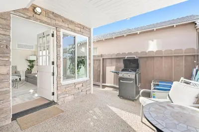 a patio with a grill and an open door at Cozy Cottage W Ac, Stylish Interior, One House From Beach By Beachview Rentals in Newport Beach