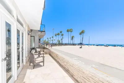 a building next to a beach with palm trees at 4Br Oceanfront W Ac, Panoramic Views In Coveted Location By Beachview Rentals in Newport Beach