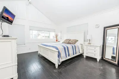 a white bedroom with a bed and a tv at 4Br Oceanfront W Ac, Panoramic Views In Coveted Location By Beachview Rentals in Newport Beach