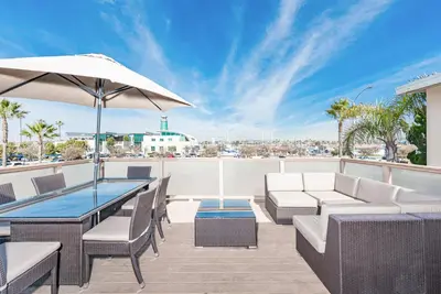 a patio with a table and chairs and an umbrella at Cozy 2Br W Large Deck, Steps From Marina Park And Beach By Beachview Rentals in Newport Beach