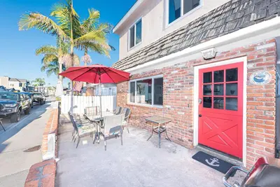 a red door on a brick building with a table and chairs at Quiet 4Br Home W Large Deck And Bbq, 2 Blocks From Sand By Beachview Rentals in Newport Beach