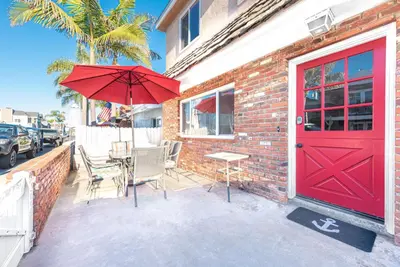 a patio with a red door and a table and chairs at Quiet 4Br Home W Large Deck And Bbq, 2 Blocks From Sand By Beachview Rentals in Newport Beach