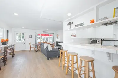 a kitchen and living room with a counter and stools at Quiet 4Br Home W Large Deck And Bbq, 2 Blocks From Sand By Beachview Rentals in Newport Beach