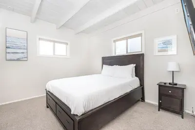 a white bedroom with a large bed and two windows at Cozy 2Br Upstairs Cottage Steps From Sand In Prime Location By Beachview Rentals in Newport Beach