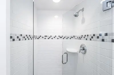 a white bathroom with a shower and a sink at 3Br Beach Cottage W Large Patio And Grill, Prime Location By Beachview Rentals in Newport Beach