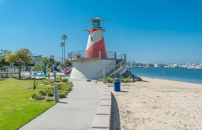 a red and white lighthouse next to a beach at 3Br Beach Cottage W Large Patio And Grill, Prime Location By Beachview Rentals in Newport Beach