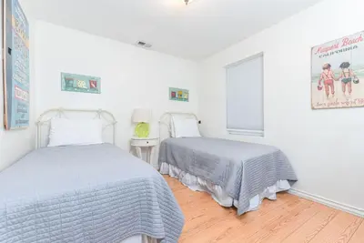 two beds in a bedroom with white walls and wood floors at Charming 3Br Beach Home W Rooftop Deck One Block From Sand By Beachview Rentals in Newport Beach