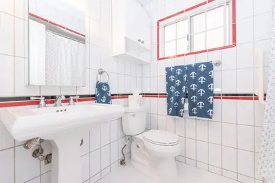 a white bathroom with a toilet and a sink at Charming 1Br Beach Cottage W Large Patio One Block To Sand By Beachview Rentals in Newport Beach