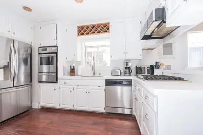 a kitchen with white cabinets and stainless steel appliances at Charming 1Br Beach Cottage W Large Patio One Block To Sand By Beachview Rentals in Newport Beach