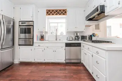 a kitchen with white cabinets and stainless steel appliances at Charming 1Br Beach Cottage W Large Patio One Block To Sand By Beachview Rentals in Newport Beach