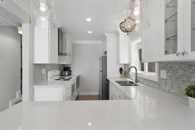 a white kitchen with white cabinets and a sink at Stylish 3Br Oceanfront W Gorgeous Views, Boardwalk Access By Beachview Rentals in Newport Beach