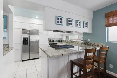 a kitchen with white cabinets and a counter with chairs at Affordable 3Br Near Beach, Walk To Shops, Dining And More By Beachview Rentals in Newport Beach