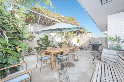a wooden table and chairs with an umbrella on a patio at Affordable 3Br Near Beach, Walk To Shops, Dining And More By Beachview Rentals in Newport Beach